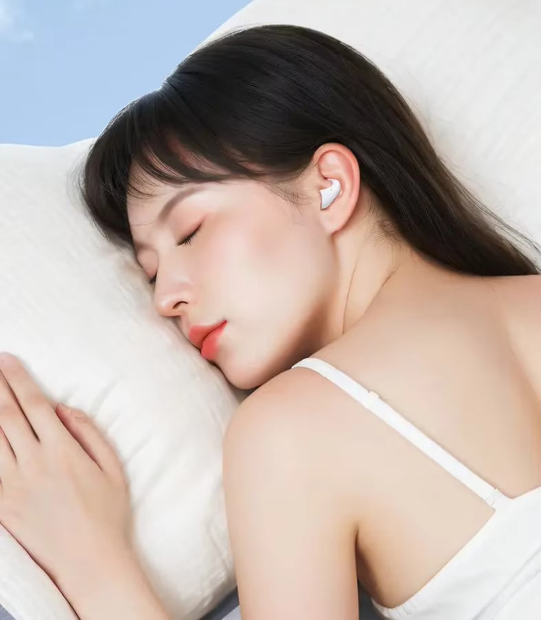A woman asleep on her side on a pillow with a Sleep Earbud in her ear