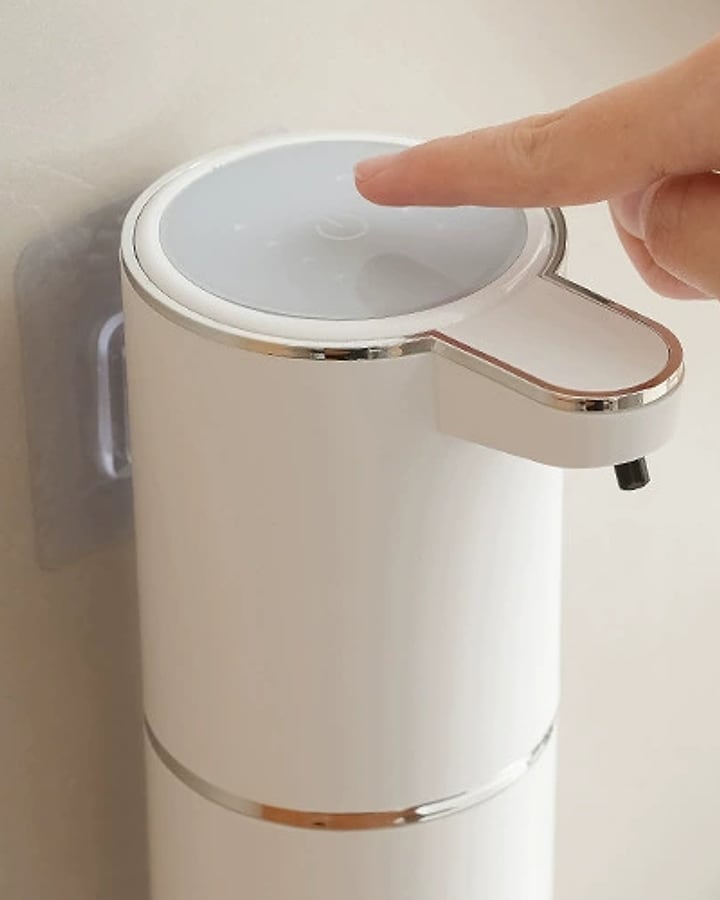 A finger pressing the button on top of the Automatic Soap Dispenser